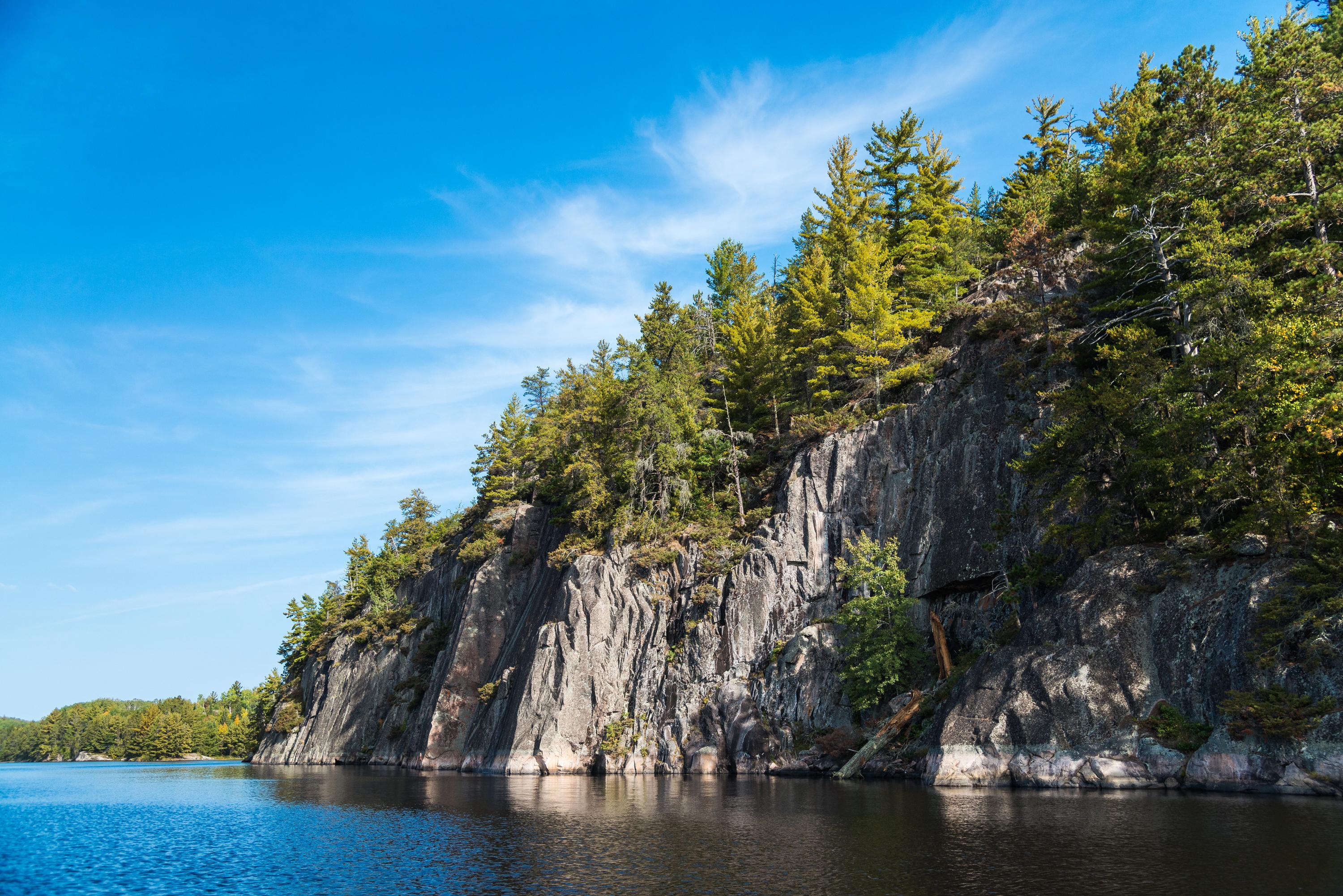 Calm lake water and forested rocky shoreline at sunset in Voyageurs National Park, Minnesota