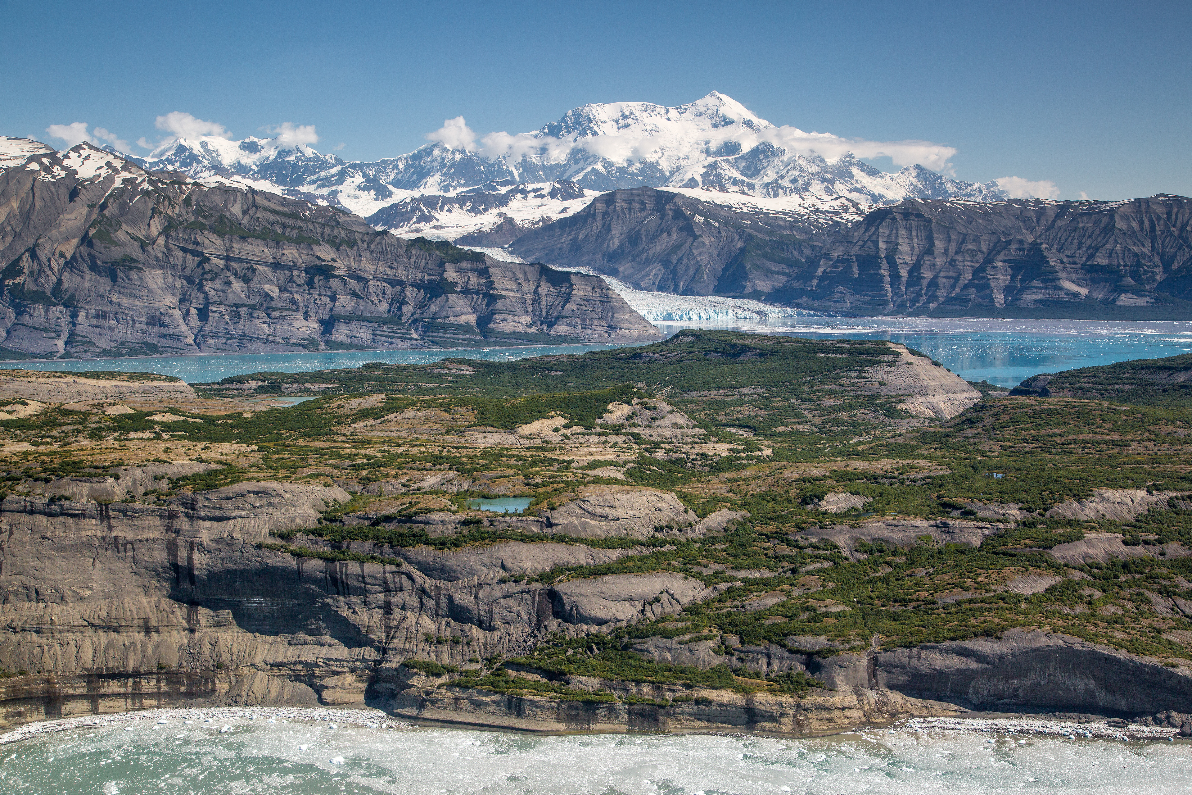 Hikers on the Root Glacier Trail below the peaks of Wrangell-St. Elias National Park in Alaska